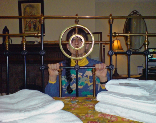 Marmaduke's Hotel, York and Impractical Beds
Marjorie looking through the rather silly bull's eye in the foot of the over-large double bed in our room at Marmaduke's Hotel in York.  Please note the TV on the right in this picture.  You can't watch TV from bed without looking through the bars at the foot of the bed.
Anahtar kelimeler: Marmadukes Hotel York bedstead Marjorie