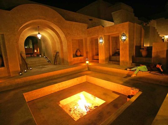 A Fire Pit in the Bab al Shams Hotel
It gets cold on the desert at night, so the Bab Al Shams Hotel had this large fire pit that they lit every evening.  Marjorie is relaxing on the right, a bit like Rousseau's [url=http://www.artelino.com/articles/henri_rousseau.asp]Sleeping Gypsy[/url].
Palabras clave: Fire Pit Bab Al Shams desert Marjorie