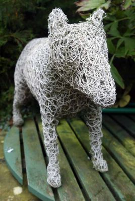 At least this dog doesn't bark
A "sculpture" of a bull terrier made from chicken wire that's then been painted white.  At one time we had this down in the flower beds (instead of standing on our well), but it scared our dogs and our doggie guests.  They didn't like a dog lurking in the bushes -- particularly one that looks like white chicken wire.
Palabras clave: Wire dog Whitecroft Bull Terrier