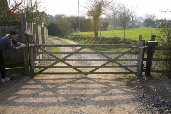 Stable Gate at Lucies Farm
Photographed from the stable yard, looking down our track (with Gregorz manually latching the gate).  The motor that should open and close the gate is on the right in this photograph.  As is shown, the gate is exposed to the elements, and wind coming down the track and from the neighbour's field hits the gate staight on.
الكلمات الإستدلالية(لتسهيل البحث): stable gate Gregorz automation gate