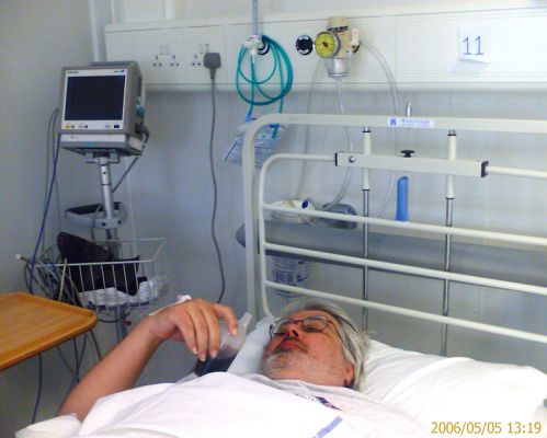 Craig in the Worcester Royal Infirmary
With my bad Achilles' tendons, I managed to slip-and-fall in our own conservatory at midnight.  I managed to limp to the couch, but at 3 AM I couldn't get up.  Two ambulances later (they needed [i]four[/i] people to lift me I was at the hospital. They did X-rays and CAT scans, and concluded that I had "soft tissue damage."  Here I am, drinking a Diet Coke from one of those little cup things.  May 5 2006
Trefwoorden: Craig Worcester Royal Infirmary slip and fall Coke