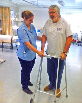 Craig Out For A Stroll
A preview of things to come?  :-(  I'd been immobilised for about 14 hours, injected with morphine and other goodies, and "log rolled" from gurney to CAT scan tray.  This is my first time up and about, complete with nurse and walker.  On the way home, I went "ouch, ouch" when Marjorie even drove over a tiny pebble in the road.  I am a true Princess. May 5 2006
Anahtar kelimeler: Craig walker nurse Worcester Royal Infirmary