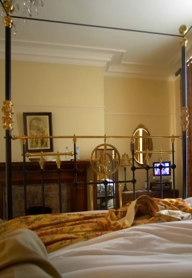 Marmadukes Luxury Hotel -- Trying to Watch TV in Bed
This overwhelming bed also made it impossible to watch the single TV in the room from bed.  Yet the bed was 80% of the room.  The single TV screen was small, and you had to look at it through the bars at the foot of the bed.  It was the most inconsiderately designed hotel room Marjorie and I had ever encountered, and the hotel management was absolutely the worst.
Λέξεις-κλειδιά: Marmadukes Luxury Hotel York four poster bed television