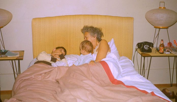 In Bed at 140 Dowsett Avenue
Me (on the left), Shauna (the baby), and Nana.  My guess is late 1955.  This isn't the best photograph -- no faces showing.  I've included it anyway because I thought the bedside table is interesting.  I love the old dial telephone, the 1950's shoji lamps.  But my favourite thing is the bottle of lager and cigarettes.  I never remember my grandmother drinking --- but [i]larger![/i]  How images can be shattered through the magnification power of Adobe Photoshop.
Anahtar kelimeler: Shauna Nana bedside table dial telephone lager Photoshop Dowsett Avenue