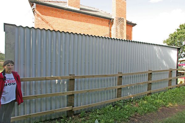 Lord's Wood Cottage Extension
The new metal extension on Lord's Wood cottage.  This photograph is taken from the east, looking slightly north-west.  The extension is shown coming right up to the fence line, which we believe encroaches upon our property.  The height of the extension can be estimated using Marjorie's height (5'6").
Ключові слова: Lord's Wood cottage extension
